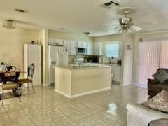 kitchen with ceiling fan, a kitchen island, white fridge, and white cabinets