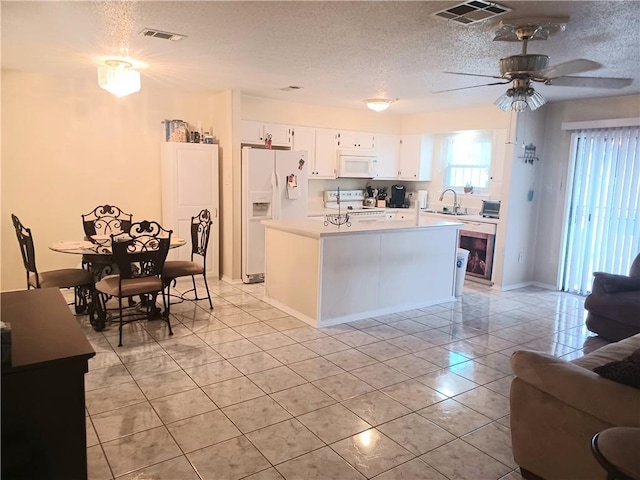 kitchen featuring light tile patterned flooring, a textured ceiling, a kitchen island, white appliances, and white cabinets