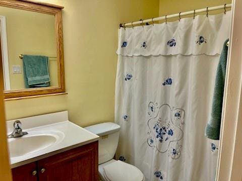 bathroom with walk in shower, vanity, and toilet