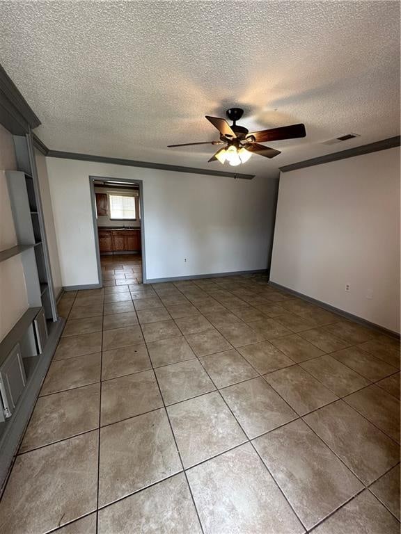 tiled spare room with crown molding, a textured ceiling, and ceiling fan