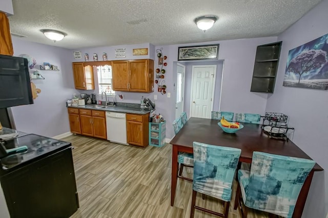 kitchen with light wood-type flooring, white dishwasher, a textured ceiling, and sink