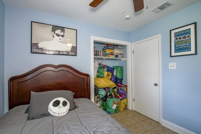 tiled bedroom with ceiling fan and a closet