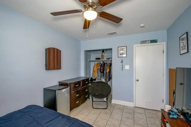 tiled bedroom featuring a closet, ceiling fan, and stainless steel refrigerator