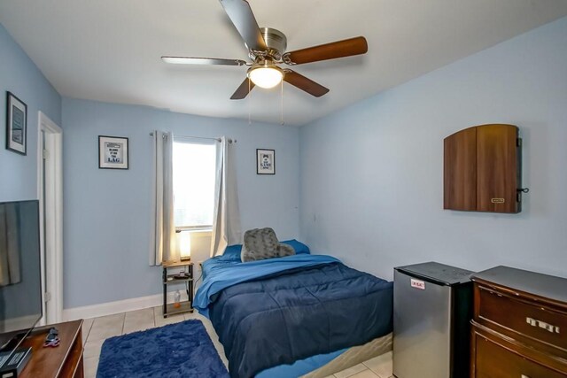 bedroom featuring ceiling fan, stainless steel refrigerator, and light tile patterned floors