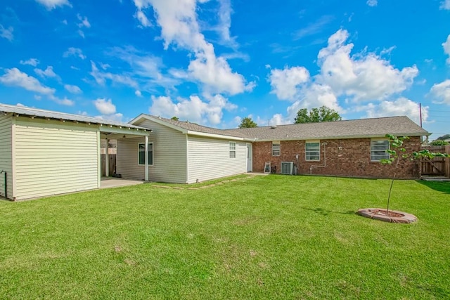 rear view of property featuring central AC unit, a lawn, and a patio