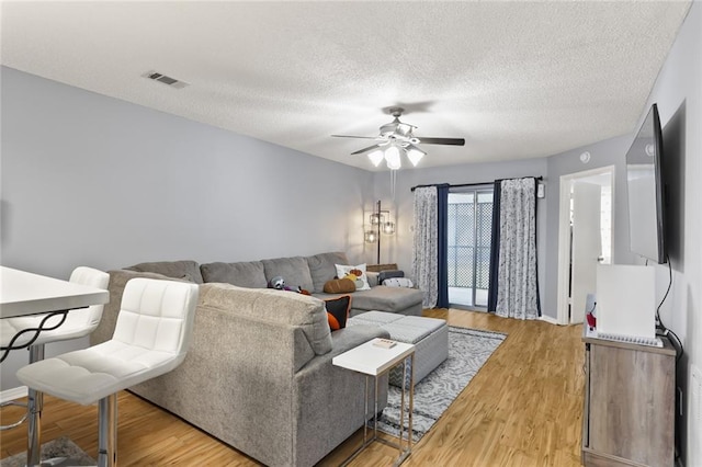 living room featuring a textured ceiling, light hardwood / wood-style flooring, and ceiling fan