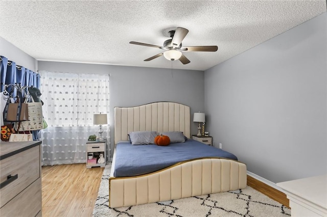 bedroom featuring ceiling fan, light hardwood / wood-style floors, and a textured ceiling