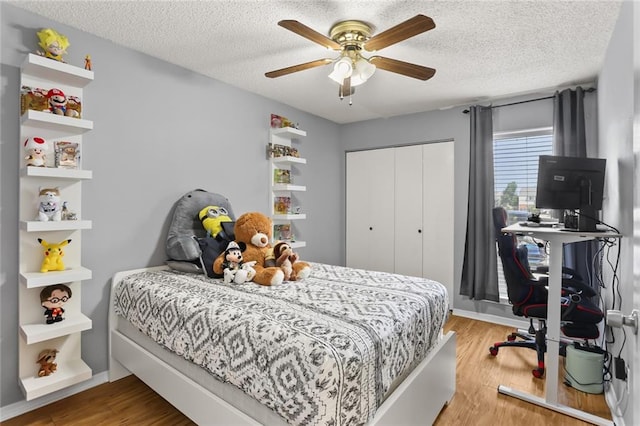 bedroom with a textured ceiling, hardwood / wood-style floors, ceiling fan, and a closet