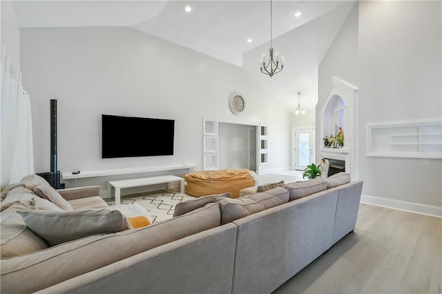 living room with high vaulted ceiling, an inviting chandelier, and light wood-type flooring