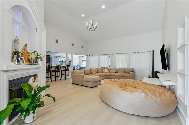 living room with high vaulted ceiling, a notable chandelier, and light wood-type flooring