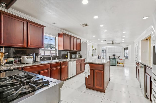 kitchen featuring a kitchen island, stainless steel appliances, ornamental molding, and ceiling fan