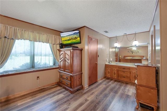 bathroom featuring a textured ceiling, wood-type flooring, ceiling fan, ornamental molding, and vanity