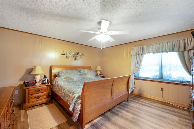 bedroom with a textured ceiling, light hardwood / wood-style flooring, and ceiling fan