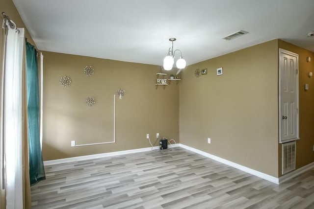 empty room featuring a notable chandelier and hardwood / wood-style floors