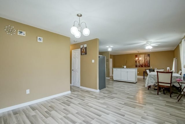 interior space featuring light wood-type flooring, white cabinets, ceiling fan with notable chandelier, and hanging light fixtures