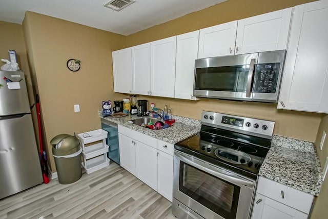 kitchen featuring white cabinets, stainless steel appliances, sink, and light hardwood / wood-style flooring