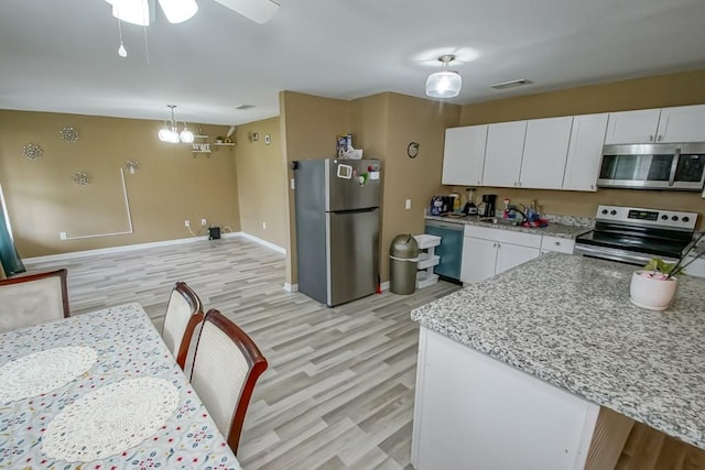 kitchen featuring light wood-type flooring, pendant lighting, ceiling fan with notable chandelier, white cabinetry, and appliances with stainless steel finishes