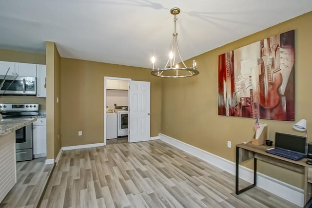 dining space featuring light wood-type flooring, an inviting chandelier, and washing machine and clothes dryer