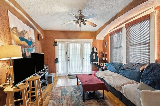 living room featuring ceiling fan, hardwood / wood-style flooring, and a textured ceiling