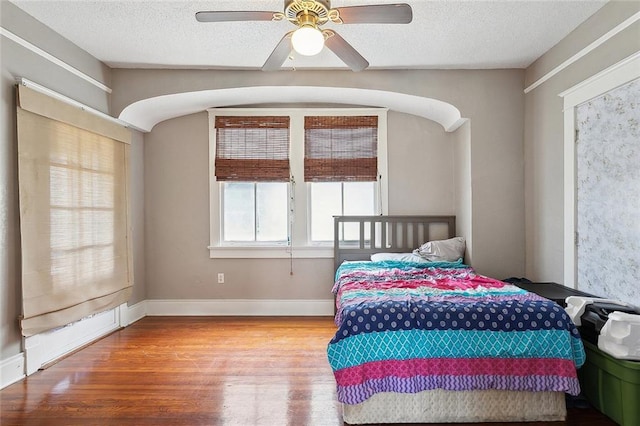 bedroom with a textured ceiling, ceiling fan, and hardwood / wood-style flooring