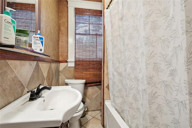 full bathroom with shower / tub combo with curtain, tile patterned flooring, tile walls, toilet, and sink