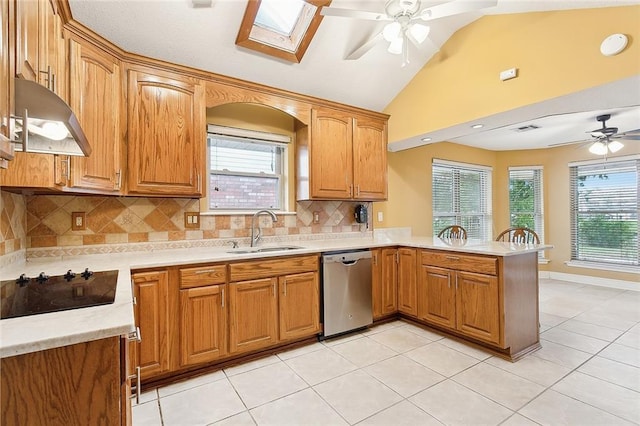 kitchen featuring vaulted ceiling with skylight, dishwasher, sink, ceiling fan, and decorative backsplash