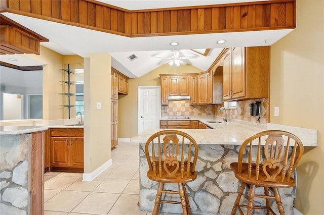 kitchen with a kitchen breakfast bar, tasteful backsplash, kitchen peninsula, sink, and ceiling fan