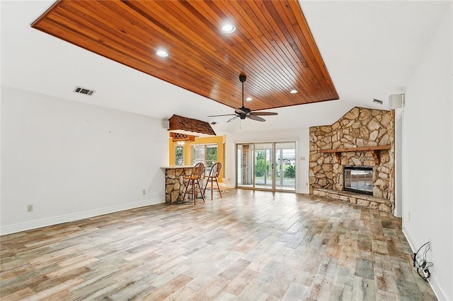 unfurnished living room with light hardwood / wood-style flooring, ceiling fan, a stone fireplace, wood ceiling, and lofted ceiling