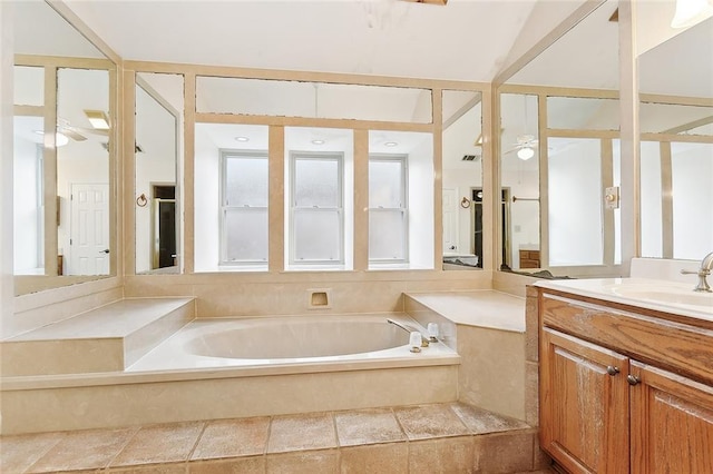 bathroom featuring vanity, a relaxing tiled tub, and ceiling fan