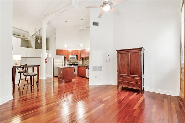 living room featuring a high ceiling, ceiling fan, and hardwood / wood-style flooring