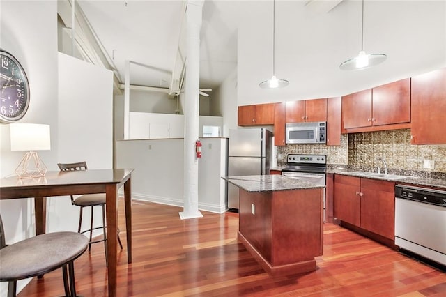 kitchen with a center island, backsplash, stainless steel appliances, and light hardwood / wood-style floors