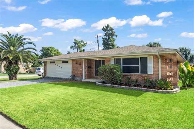 ranch-style home with brick siding, roof with shingles, and a front yard