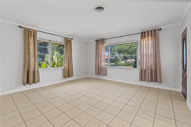 tiled empty room featuring a wealth of natural light and crown molding