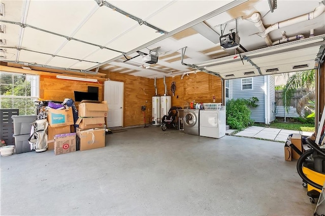 garage featuring washer and clothes dryer, a garage door opener, wooden walls, and water heater