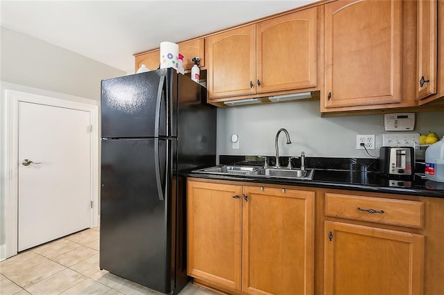 kitchen with black fridge, light tile patterned floors, and sink