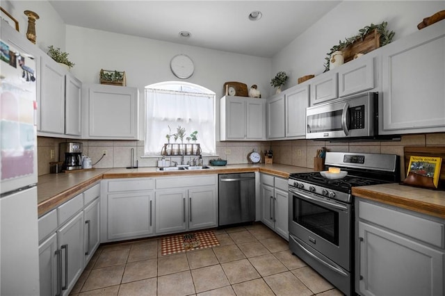 kitchen featuring appliances with stainless steel finishes, light tile patterned floors, backsplash, and sink