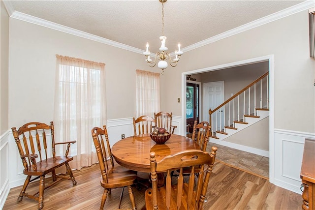 dining space with a textured ceiling, light wood-type flooring, crown molding, and a notable chandelier