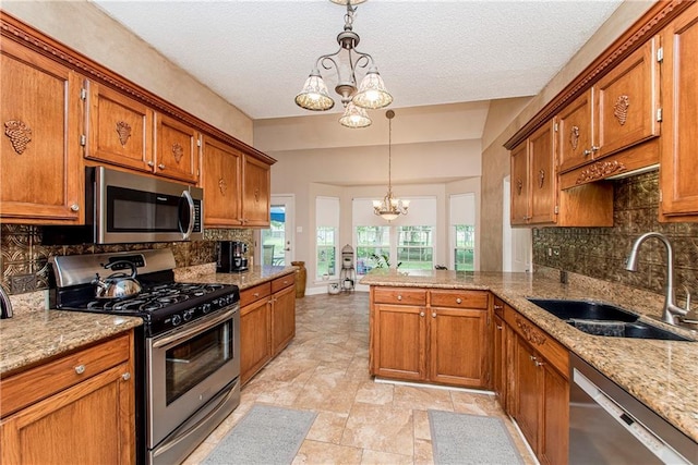 kitchen featuring pendant lighting, sink, stainless steel appliances, and a chandelier