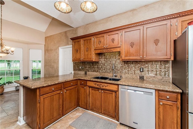 kitchen with pendant lighting, lofted ceiling, sink, appliances with stainless steel finishes, and kitchen peninsula