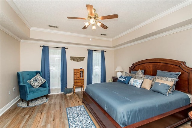 bedroom featuring a raised ceiling, crown molding, ceiling fan, a textured ceiling, and light hardwood / wood-style floors