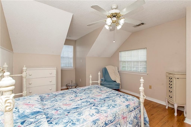 bedroom with hardwood / wood-style floors, a textured ceiling, ceiling fan, and lofted ceiling