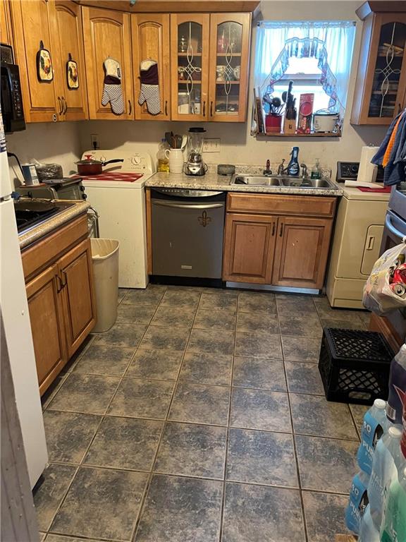 kitchen featuring dishwasher, washer / dryer, sink, and dark tile patterned floors