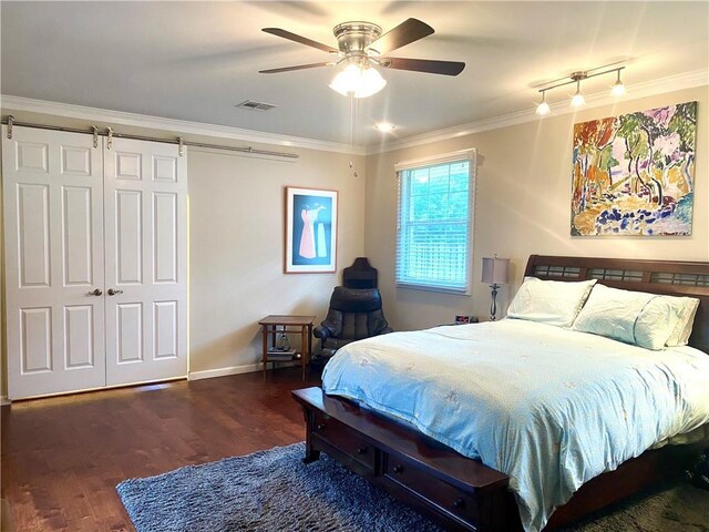 bedroom featuring ornamental molding, dark hardwood / wood-style flooring, ceiling fan, and a barn door