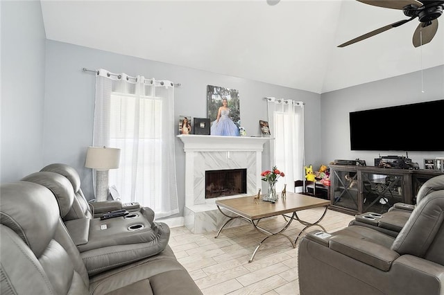 living room with a premium fireplace, vaulted ceiling, ceiling fan, and light hardwood / wood-style floors