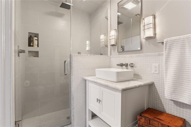 bathroom featuring walk in shower, vanity, and tile walls