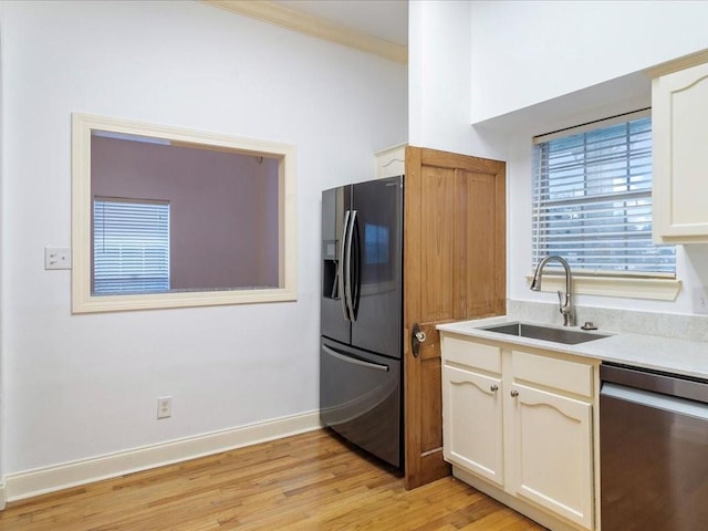 kitchen featuring ornamental molding, appliances with stainless steel finishes, light hardwood / wood-style flooring, and sink