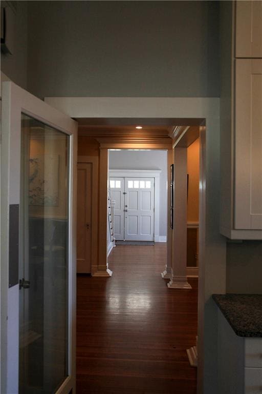 hallway with decorative columns, ornamental molding, and dark hardwood / wood-style floors