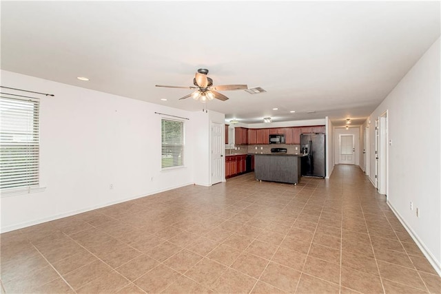 unfurnished living room with ceiling fan, light tile patterned floors, and plenty of natural light