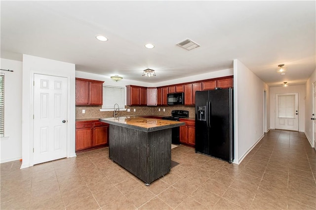 kitchen featuring light tile patterned floors, backsplash, a breakfast bar, black appliances, and a center island