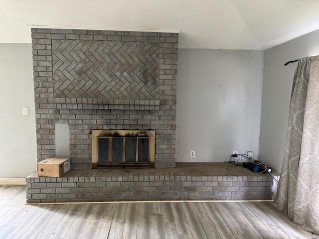 unfurnished living room featuring lofted ceiling, wood finished floors, and a fireplace